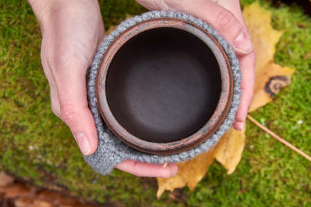 Empty mug in womens hands. View from above against the background of green moss. Picnic, hike, cozy.の写真素材