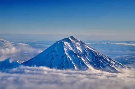 View of the snow-capped volcano from the aircrafts illuminator. Top dormant volcano above the clouds.の写真素材