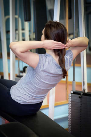 Cute girl work out at the gym. The girl is training her abs and doing body twistsの写真素材