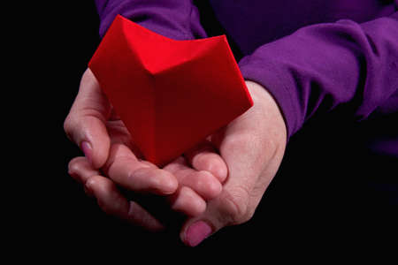 Symbol of the heart in womens palms. Red paper heart in woman hands. Close-up.の写真素材