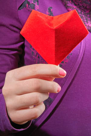 Symbol of the heart in womens palms. Red paper heart in woman hands. Close-up.の写真素材
