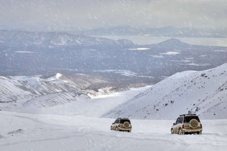 The two SUV drives through snow-covered mountain valley with deep snow after a snowstorm.の写真素材