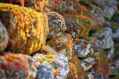 Masonry, selective focus. A wall of old muddy rough stones in the sunlight.の写真素材