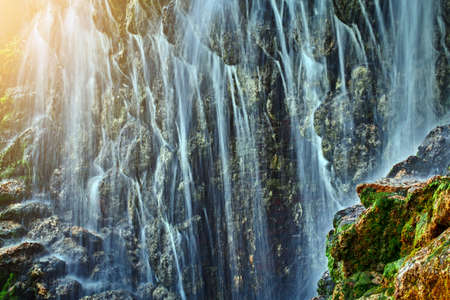 A large waterfall in a cave in the sun's raysの写真素材