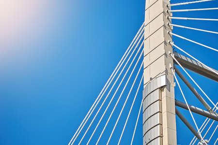 Ropes of a cable-stayed bridge against a blue sky.の写真素材
