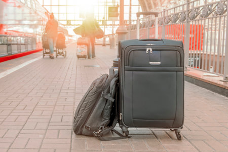 A suitcase and backpack stand on the platform of the railway station in the rays of the rising sun. Travel concept.の写真素材