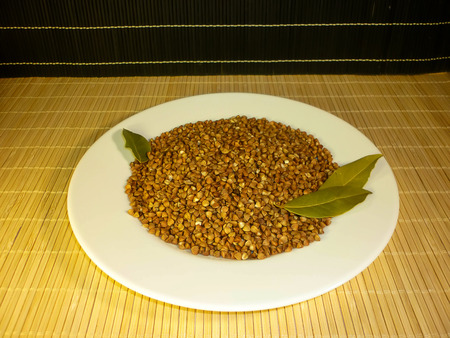 buckwheat in a white plate with a laurel leafの写真素材