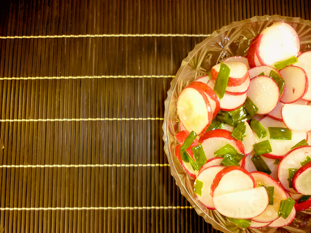 red radish with green cibules in a crystal plateの写真素材