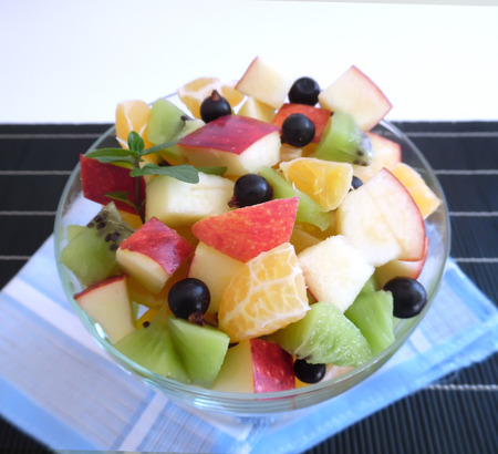 fruit salad on a darkbackground orange kiwi apple mandarinの写真素材
