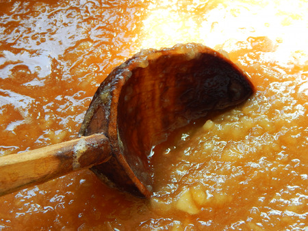 apple jam is brewed in a bowl and is stirred with a wooden spoon.の写真素材