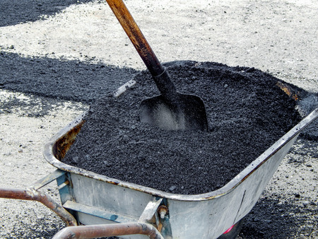 trolley full of asphalt with a shovel on a sunny day.の写真素材