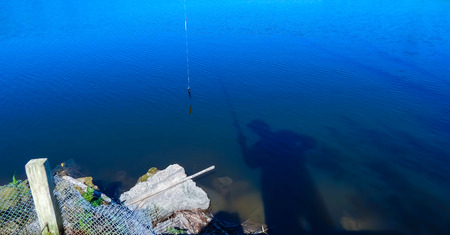 reflection of a fisherman in the water fishing on the riverの写真素材