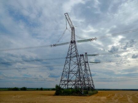 high voltage tower standing in a field with wires.の写真素材