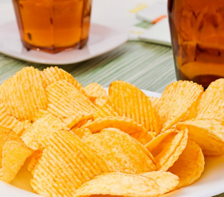 Crispy potato chips in a wicker bowl on old kitchen table.の素材