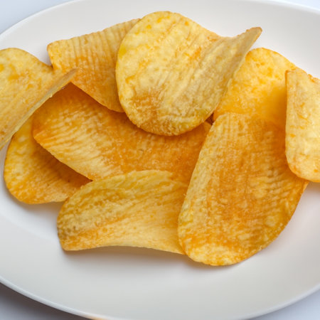 Crispy potato chips in a wicker bowl on old kitchen table.の素材