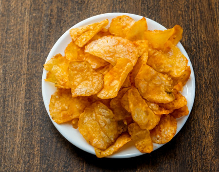 Crispy potato chips in a wicker bowl on old kitchen table.の素材