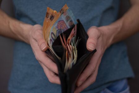 Young man shows his wallet with a lot of money. Teenager with money to spendの写真素材
