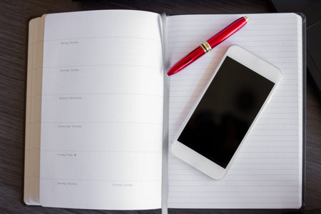 Close up of smart phone and paper Notebook on a modern office desk. Concept for connecting devices...