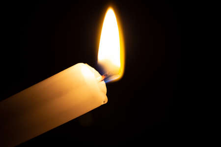 diagonal burning small candle with black backgroundの写真素材
