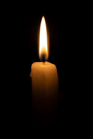 small yellow burning candle fading in the darknessの写真素材