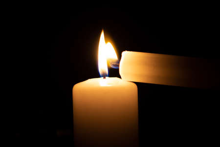 igniting a smaller candle with a big oneの写真素材