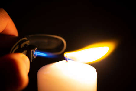igniting a white candle with a storm lighterの写真素材