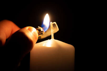 igniting a big white candle with a lighterの写真素材