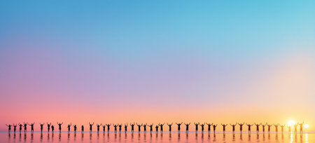 Silhouettes of people with raised arms reflected in shallow water at sunset or sunrise with a colorful skyの素材