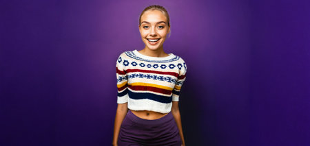 smiling young woman with blonde hair in a striped knitted top on a purple backgroundの素材
