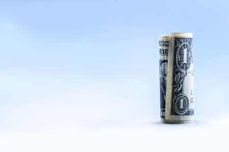 Rolled one dollar banknote stand vertical.Blue background.の写真素材