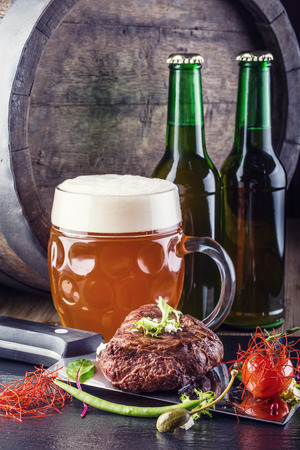 Beef steak withvegetable decoration. Beer barrel with beer glass and bottleの写真素材