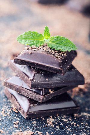 Chocolate. Black chocolate. A few cubes of black chocolate with mint leaves. Chocolate slabs spilled from grated chockolate powder.の写真素材