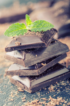 Chocolate. Black chocolate. A few cubes of black chocolate with mint leaves. Chocolate slabs spilled from grated chockolate powder.の写真素材