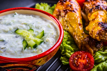 Tzatziki sauce. Tzatziki dressing. Tzatziki dressing with grilled chicken legs and fresh vegetable,lettuce leaf and cherry tomatoes. Grilled chicken legs, lettuce and tomatoes. Mediterranean cuisineの写真素材