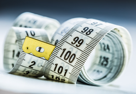 Curved measuring tape. Measuring tape of the tailor. Closeup view of white measuring tapeの写真素材