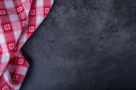 Top view of checkered kitchen tablecloth on granite -  concrete - stone background. Free space for...