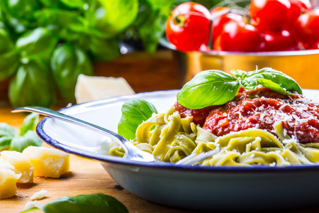 Pasta. Italian and Mediterranean cuisine. Pasta Fettuccine with tomato sauce basil leaves garlic and parmesan cheese. An old home kitchen with old kitchen utensils. Portion of on a fork pasta with tomato sauce and basil leaves.の写真素材