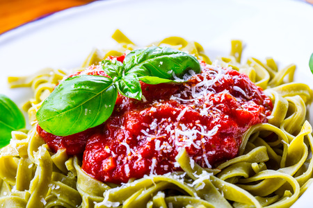 Pasta. Italian and Mediterranean cuisine. Pasta Fettuccine with tomato sauce basil leaves garlic and parmesan cheese. An old home kitchen with old kitchen utensils. Portion of on a fork pasta with tomato sauce and basil leaves.の写真素材