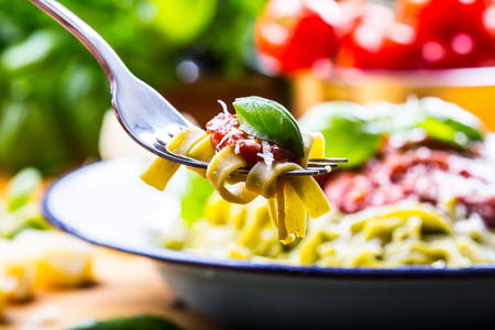 Pasta. Italian and Mediterranean cuisine. Pasta Fettuccine with tomato sauce basil leaves garlic and parmesan cheese. An old home kitchen with old kitchen utensils. Portion of on a fork pasta with tomato sauce and basil leaves.の写真素材