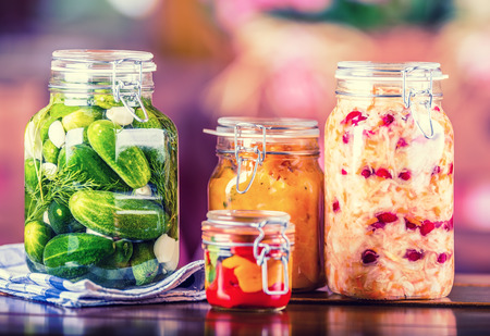 Preserving. Pickles jars. Jars with pickles, pumpkin dip, white cabbage, roasted red yellow pepper. Pickled Vegetables. Vegetable being prepared for preserving. Toned image.の写真素材