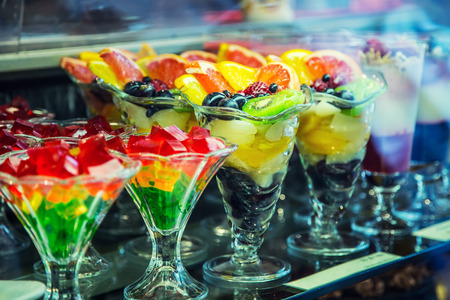 Colloured fresh summer fruits and gelatin sweet cups in confectionery shop.の写真素材
