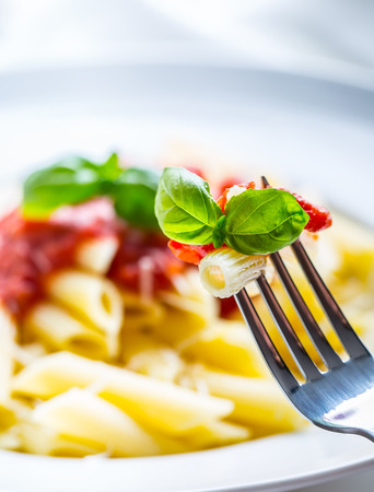 Pasta Penne with Tomato Bolognese Sauce, Parmesan Cheese and Basil on a Fork. Mediterranean food.Italian cuisine.の写真素材