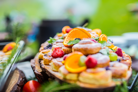 Catering buffet food outdoor. Cakes colorful fresh fruits berries oranges grapes and herb decorations.の写真素材