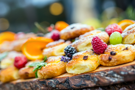 Catering buffet food outdoor. Cakes colorful fresh fruits berries oranges grapes and herb decorations.の写真素材
