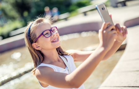 Selfie. Beautiful cute young girl with braces and glasses laughing for a selfie.の写真素材