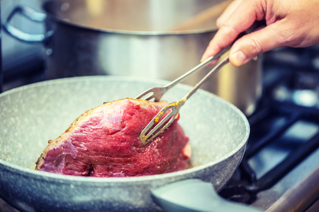 Beef steak. Chef in a restaurant kitchen use ceramic pan for preparation of beef steak.の写真素材