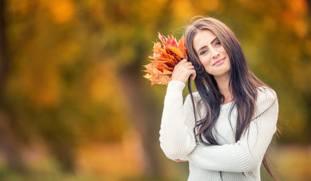Young attractive woman with bouquet autumn leaves in hand. Fall.の写真素材