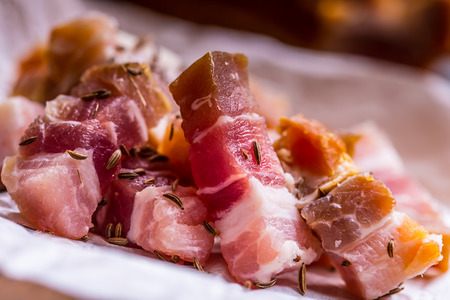 Raw smoked bacon slices on wooden board with cumin and herbs.の写真素材