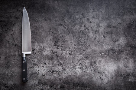 Kitchen knife on concrete or wooden board.