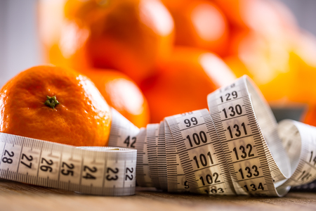 Fresh tropical fruit and measure tape.Tangerines, peeled tangerine and tangerine slices on a blue cloth. Mandarine juice.の写真素材